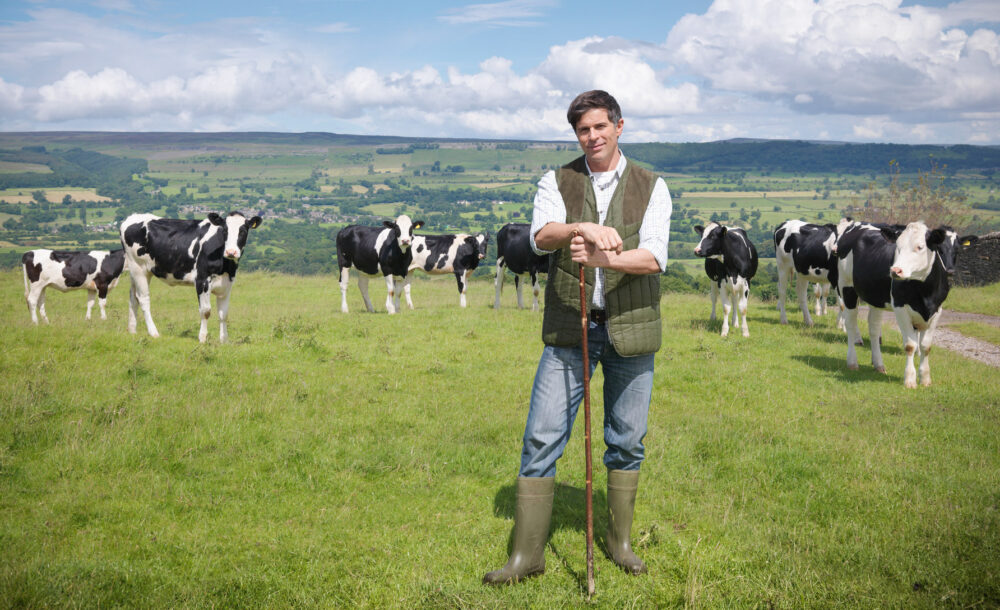 Farming for the future. Portrait of farmer and cows in field